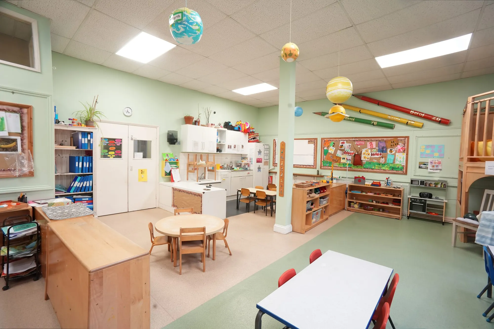 The open classroom with a round table, shelves and the nursery kitchen area