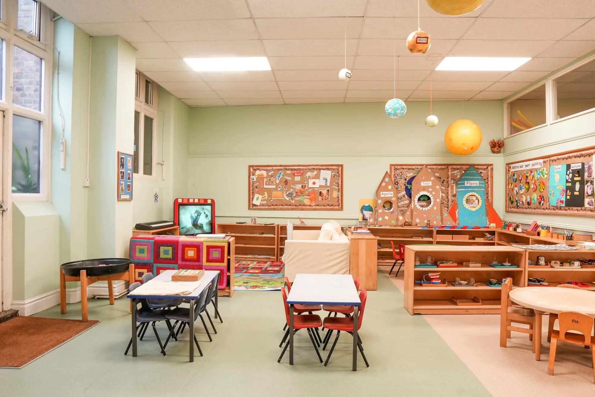 The Angel classroom with hanging planets, cardboard rockets and child-sized tables