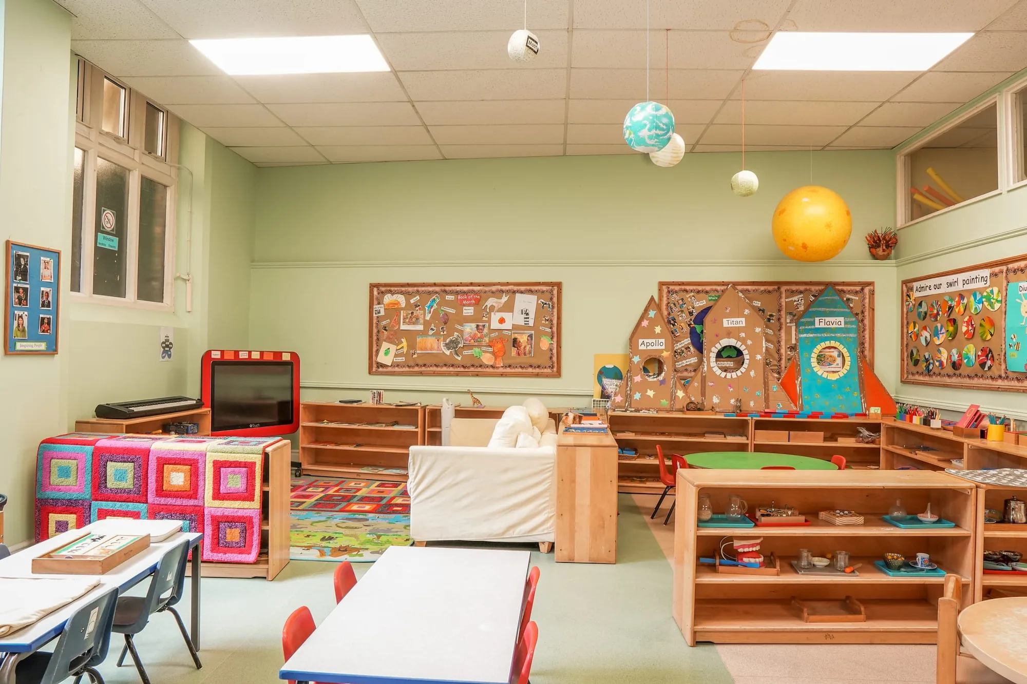 A sofa, rugs and bookshelves in the Angel reading area beneath hanging planets
