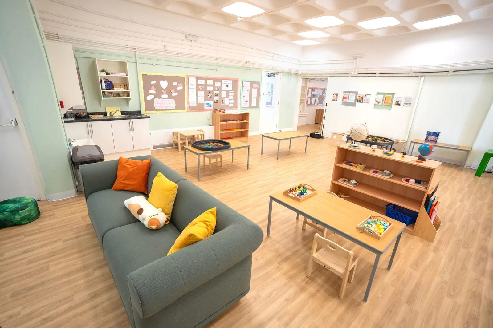 The Abbey Road main room, with a sofa, activity tables and low Montessori shelves
