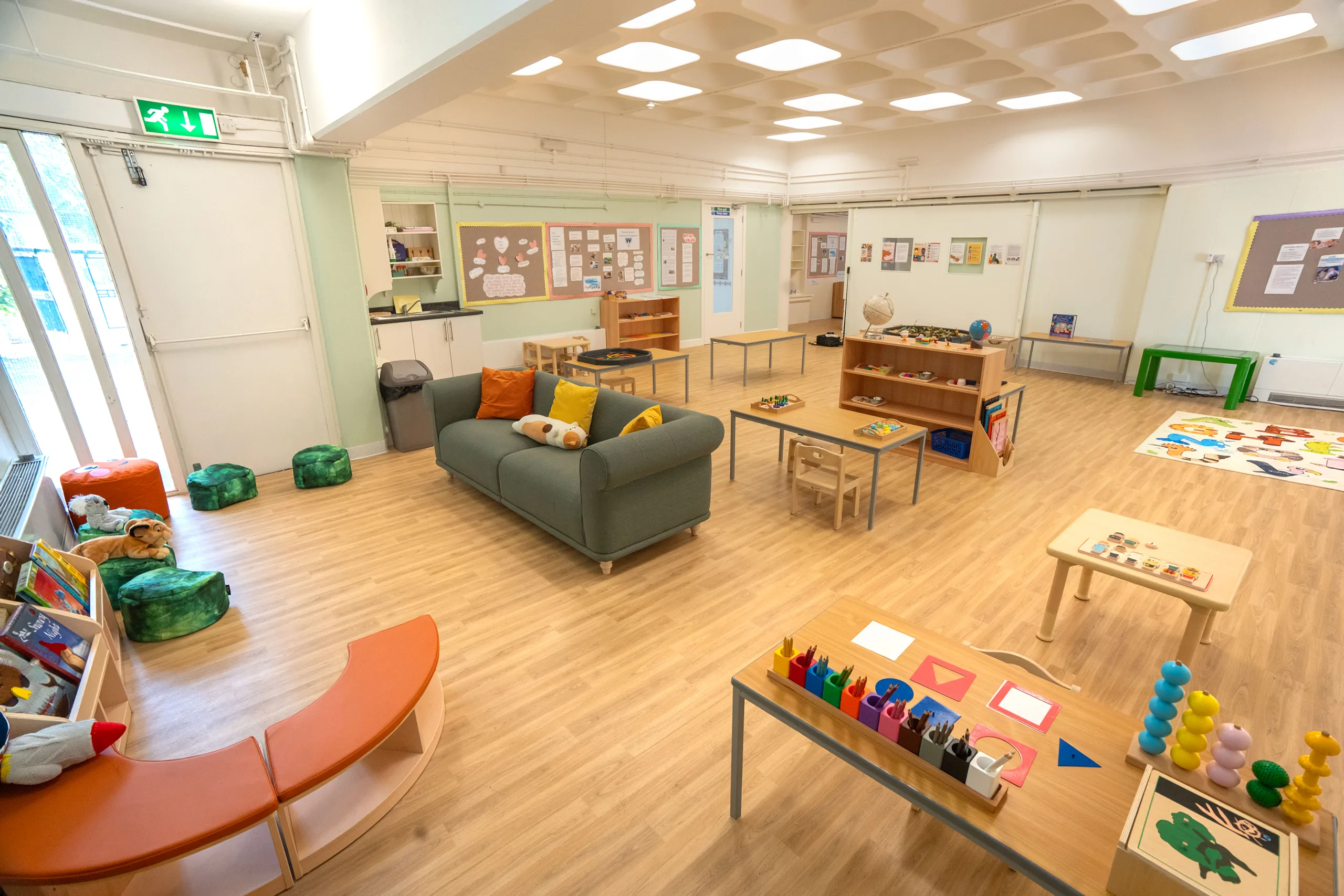 The main Abbey Road classroom, with low Montessori shelves, activity tables and a sofa